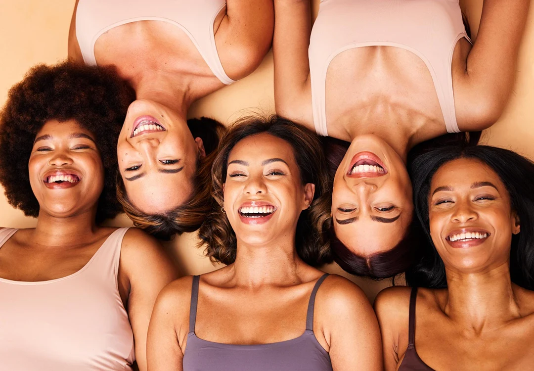 Mulheres com diferentes tonalidades de pele sorrindo lado a lado